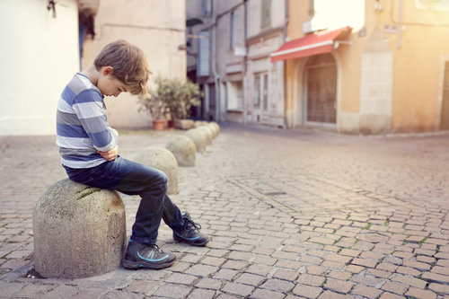 lonely child sitting on a street corner