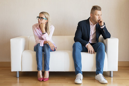 unhappy couple sitting on white couch
