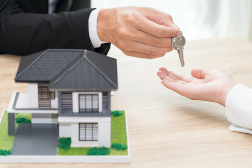 Businessman or sale man giving a house key to woman - buying home concept.