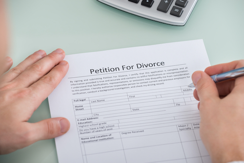 Close-up Of Person Hand Over Petition For Divorce Form
