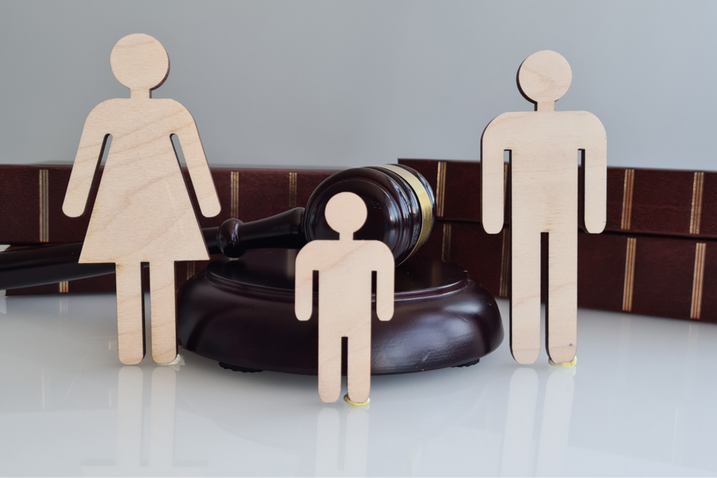 Wooden silhouettes of family with gavel and law books in backgorund